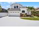 Two story home featuring an attached two car garage, neutral paint, decorative brick detail, and tropical landscaping at 14423 Tambourine Dr, Orlando, FL 32837