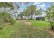 Large back yard showing a grass lawn, trees, fence, and planting bed at 16103 Denham Ct, Clermont, FL 34711
