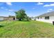 Wide shot of a green backyard, featuring a tree, fence, and blue skies at 1647 Crestlawn Ave, Orlando, FL 32811
