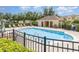 Well-kept community pool with lounge chairs and a pool house behind a black metal fence and lush landscaping at 178 Windflower Way, Oviedo, FL 32765
