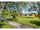 Welcoming home with a verdant lawn, mature trees, and convenient carport at 1901 Loch Berry Rd, Winter Park, FL 32792