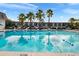 Large community pool reflecting the sky and palm trees on a clear day at 1940 S Conway Rd # 8, Orlando, FL 32812