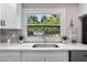 Close-up of kitchen window, white quartz countertops, marble backsplash, and stainless steel sink at 209 N 14Th St, Leesburg, FL 34748