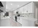 Bright kitchen features all white cabinetry, stainless steel appliances, white quartz countertops, and tiled backsplash at 209 N 14Th St, Leesburg, FL 34748
