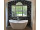 Soaking tub with decorative tile accent wall and large window with backyard view at 2258 Rickover Pl, Winter Garden, FL 34787