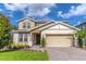 Charming two-story home with landscaped yard, tan siding, and a brick driveway under a sunny sky at 2335 Green Symphony Pl, Oviedo, FL 32765