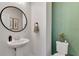 Stylish powder room with a pedestal sink, round mirror, and vibrant green accent wall at 2335 Green Symphony Pl, Oviedo, FL 32765