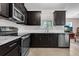 Well-lit kitchen boasts stainless steel appliances, dark cabinets, granite countertops, and tile backsplash at 2502 Seven Oaks Dr, St Cloud, FL 34772
