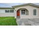 Close-up of a home's front facade with a red door, arched entryway, and freshly cut lawn at 26 Channing Ave, Orlando, FL 32811