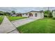 Inviting single-story house boasts a well-manicured lawn, long driveway, and neutral exterior paint at 26 Channing Ave, Orlando, FL 32811