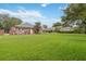 Large backyard featuring a covered patio, lush green lawn, and mature landscaping at 3215 Greens Ave, Orlando, FL 32804