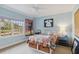 Bedroom with light blue walls, neutral carpet, patterned bedding, and a view through the window at 3215 Greens Ave, Orlando, FL 32804