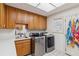 Bright laundry room featuring a tile floor, stainless steel washer and dryer, wood cabinets, and lots of counter space at 3215 Greens Ave, Orlando, FL 32804