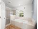 Bright bathroom featuring a soaking tub beneath a window and a glass-enclosed shower at 442 Churchill Ct, Kissimmee, FL 34759