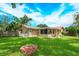 A well-maintained backyard features a brick fire pit, lush grass, and a charming tan home at 4739 Indian Gap Dr, Orlando, FL 32812