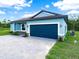 Side view of a blue home with stone accents, a spacious two-car garage, and well-maintained landscaping at 527 Rio Grande Dr, Poinciana, FL 34759