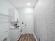 Laundry room with white cabinets, modern sink, quartz countertops, and stylish penny tile accent wall at 527 Rio Grande Dr, Poinciana, FL 34759