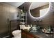 Sleek bathroom boasts unique textured wall tiles, a glass bowl sink and a round lighted mirror at 5467 Vineland Rd # 6110, Orlando, FL 32811