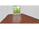 Bright bedroom featuring wood floors and sliding glass doors to a balcony with lush green views at 6052 Village Cir # 6052, Orlando, FL 32822