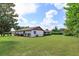 Wide shot showcasing the expansive green backyard, featuring a white house and blue skies at 8988 Angelica Dr, Orlando, FL 32836