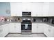 Well-lit kitchen featuring white cabinets, granite countertops, and stainless steel appliances at 9014 Stinger Dr, Davenport, FL 33896