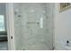 An elegant glass shower enclosure shows marble tile, modern fixtures and features convenient shelving at 9257 Outlook Rock Trl, Windermere, FL 34786
