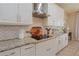 Modern kitchen features white cabinets, granite countertops, a stainless steel range hood, and herringbone backsplash at 9257 Outlook Rock Trl, Windermere, FL 34786