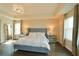 A beautifully staged primary bedroom showcases a tray ceiling, wood floors, a chandelier, and large windows at 9257 Outlook Rock Trl, Windermere, FL 34786