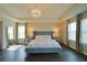 A beautifully staged primary bedroom showcases a tray ceiling, wood floors, a chandelier, and large windows at 9257 Outlook Rock Trl, Windermere, FL 34786