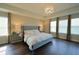 A beautifully staged primary bedroom showcases a tray ceiling, wood floors, a chandelier, and large windows at 9257 Outlook Rock Trl, Windermere, FL 34786