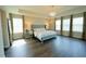 A beautifully staged primary bedroom showcases a tray ceiling, wood floors, a chandelier, and large windows at 9257 Outlook Rock Trl, Windermere, FL 34786