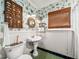 Stylish bathroom showcasing bird-themed wallpaper, pedestal sink, and classic green tiled floor at 1008 Delaney Park Dr, Orlando, FL 32806