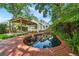 Secluded backyard pool with a brick surround, pergola with swing, and lush landscaping perfect for outdoor relaxation at 1008 Delaney Park Dr, Orlando, FL 32806