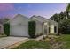 Charming single-story home featuring a two-car garage, modern landscaping, and a well-maintained lawn at sunset at 103 Gleason Cv, Sanford, FL 32773