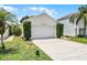 A one story home with a white, two car garage and green landscaping with palm trees on a sunny day at 103 Gleason Cv, Sanford, FL 32773