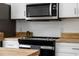 Up close view of stainless steel microwave and black cooktop with butcher block countertops and white cabinets at 103 Gleason Cv, Sanford, FL 32773