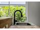 Close-up of a modern black faucet and stainless steel kitchen sink with a large window view at 103 Gleason Cv, Sanford, FL 32773