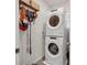 Efficient laundry room features stacked washer and dryer unit, wooden shelving, and utility hooks for storage at 115 Duchess Rd, Deland, FL 32724