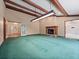 A spacious living room with exposed beams, a fireplace, and green carpet at 137 Hickory Ridge Cir, Lake Mary, FL 32746