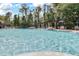 Large community pool with ample seating and umbrellas surrounded by lush green trees at 14474 Prunningwood Pl, Winter Garden, FL 34787