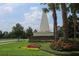 Community entrance featuring a prominent monument with landscaped gardens and palm trees at 14474 Prunningwood Pl, Winter Garden, FL 34787