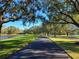 Scenic walking path lined with mature trees and green lawns beside a tranquil lake at 14474 Prunningwood Pl, Winter Garden, FL 34787