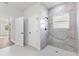 Modern bathroom featuring tiled shower, neutral color palette, and a glimpse of a bright bedroom at 16730 Sw 50Th Cir, Ocala, FL 34473
