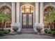 Elegant front door with decorative glass panels, flanked by columns, windows, and manicured greenery at 1810 Oakbrook Dr, Longwood, FL 32779