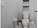 Functional half bathroom with a toilet, floating shelves, and neutral gray walls at 2620 Waterline St, Kissimmee, FL 34743