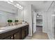Well-lit bathroom with double vanity, framed mirrors, and a glass-enclosed shower at 2620 Waterline St, Kissimmee, FL 34743