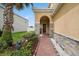 Charming front entrance featuring stone accents, brick pathway, and beautifully landscaped flowerbeds at 2659 Magpie Way, Sanford, FL 32773