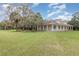 Single-story home with a wraparound porch and expansive green lawn surrounded by mature trees at 2691 Phillips Rd, Christmas, FL 32709