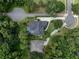 An aerial view of a home with solar panels on the roof and a private swimming pool surrounded by lush greenery at 2750 Lee Shore Loop, Orlando, FL 32820
