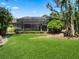 Spacious backyard with lush green lawn, mature trees, and a screened-in patio, offering a serene outdoor oasis at 2750 Lee Shore Loop, Orlando, FL 32820